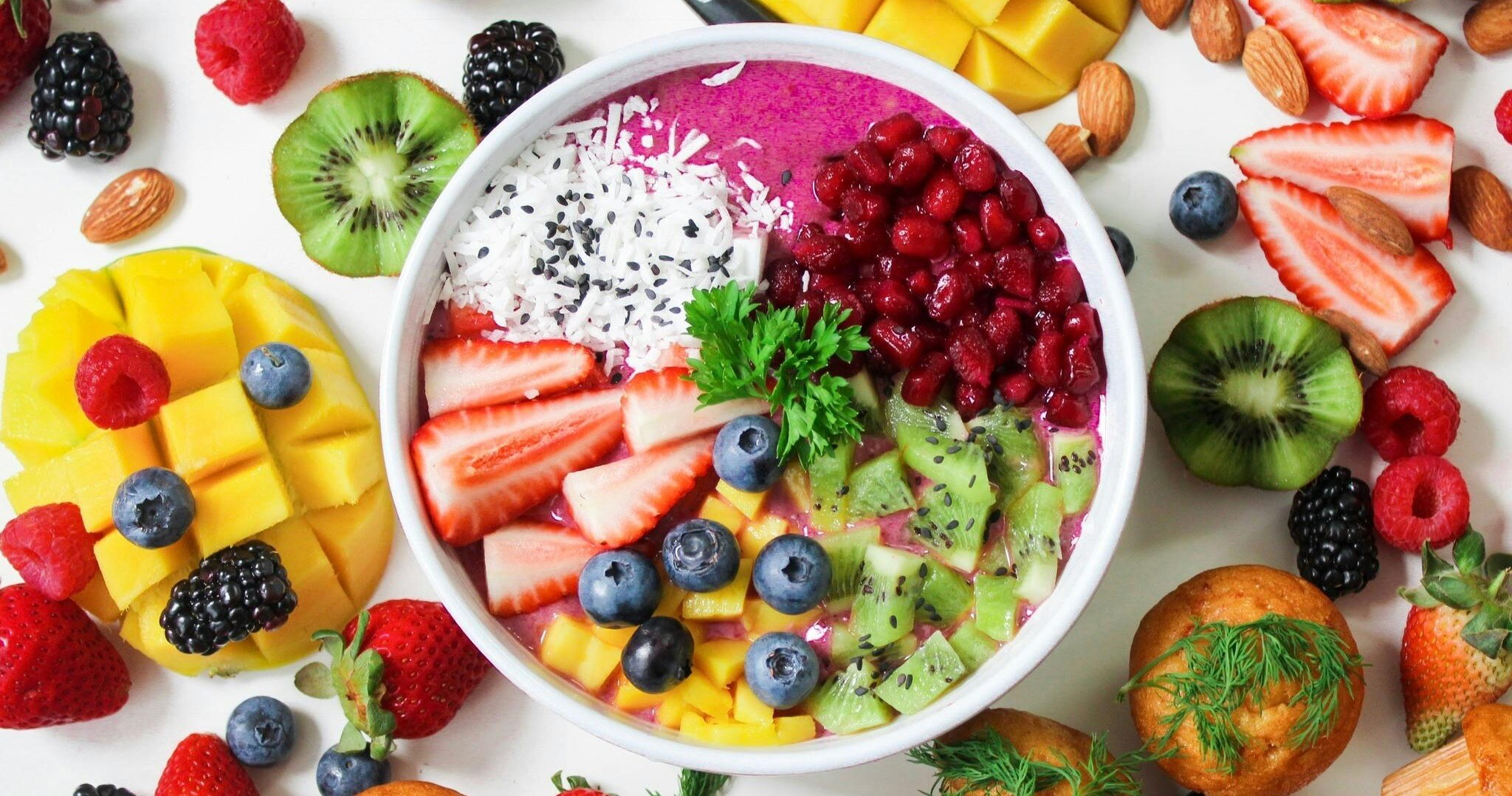 Colorful bowl of fiber-rich fruits like strawberries, blueberries, kiwi, and mango, with nuts and whole-grain muffins for a high-fiber meal-