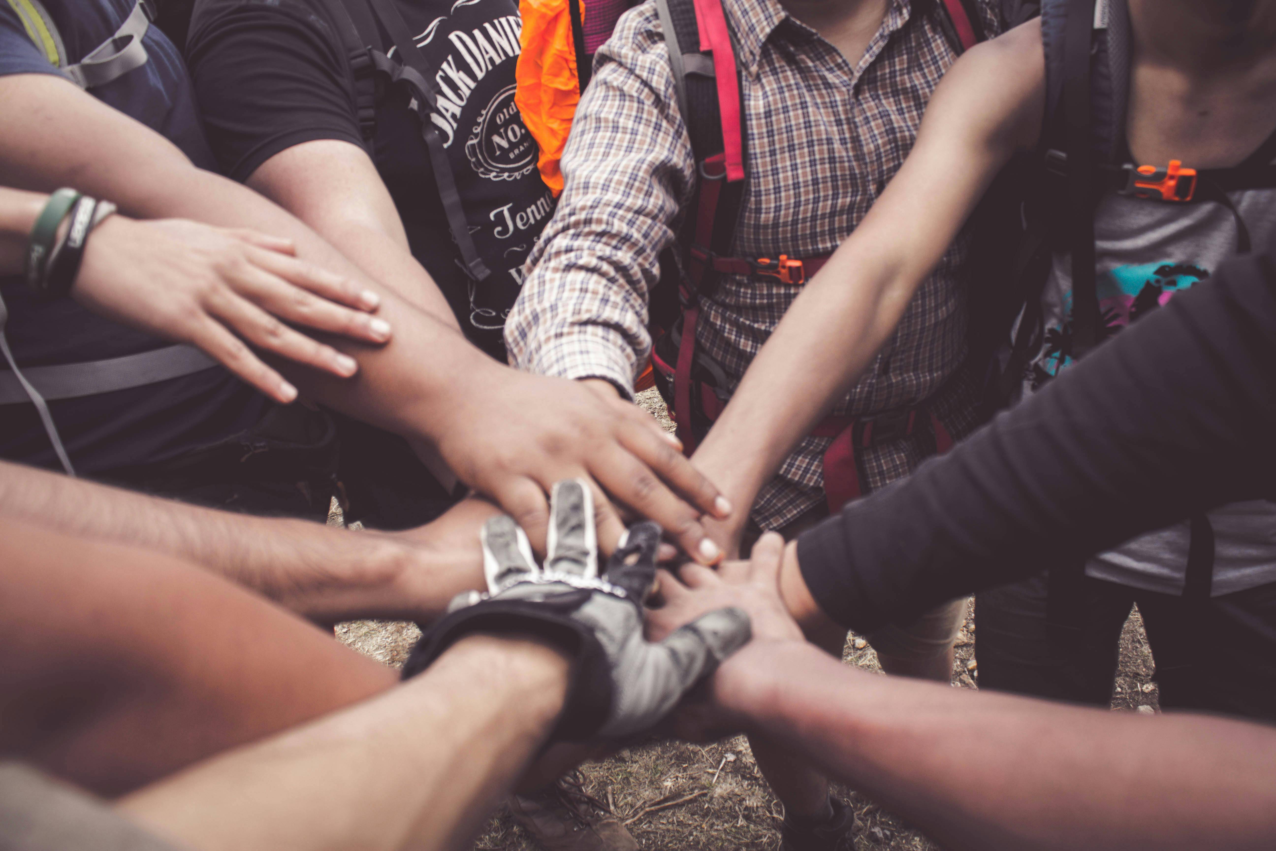 A group joining hands to symbolize teamwork and unity across diverse backgrounds.