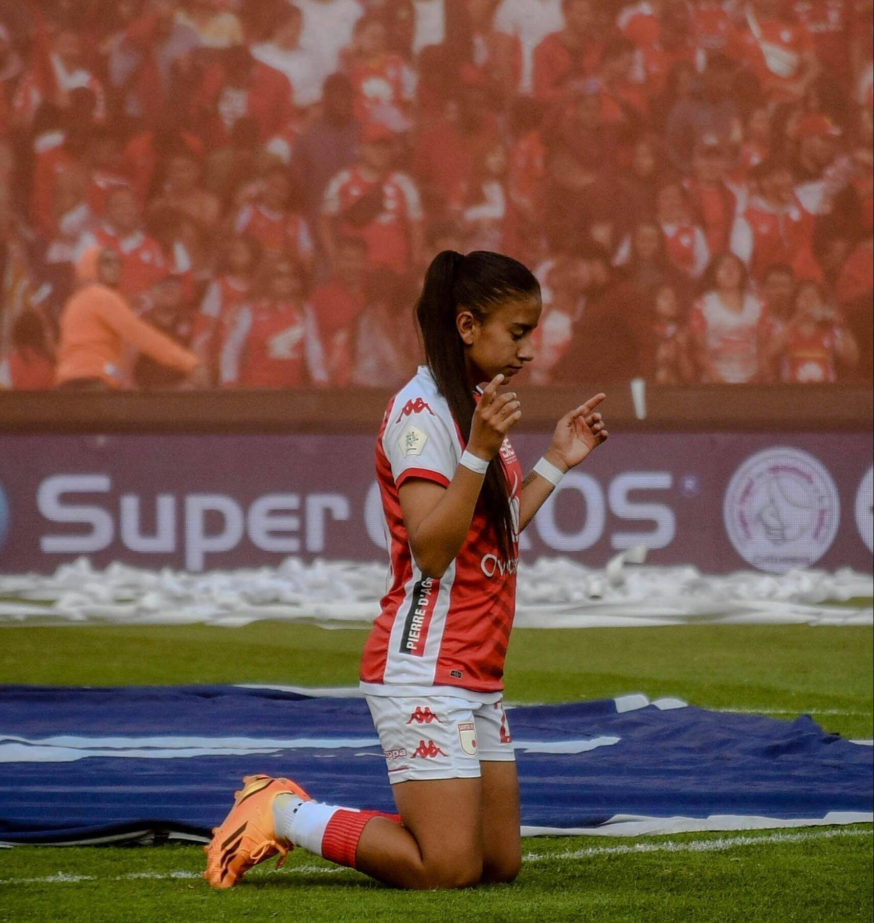 A soccer player kneels in prayer, displaying faith on the field.